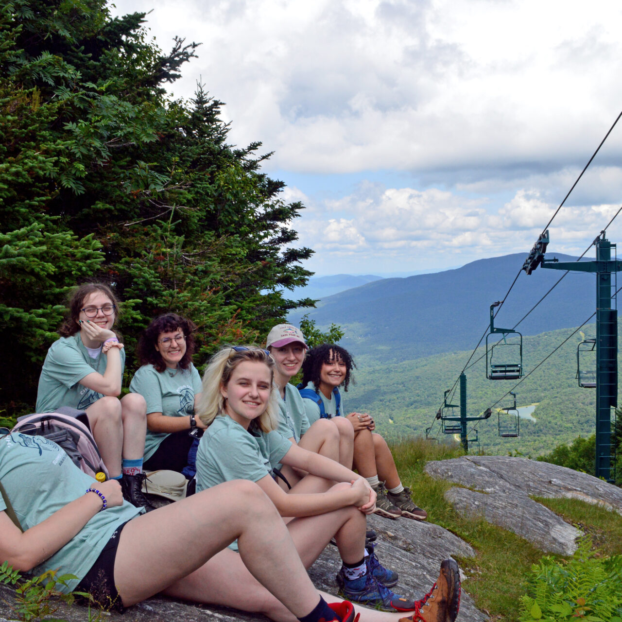 Group of students resting on rocks at a ski resort during summer time