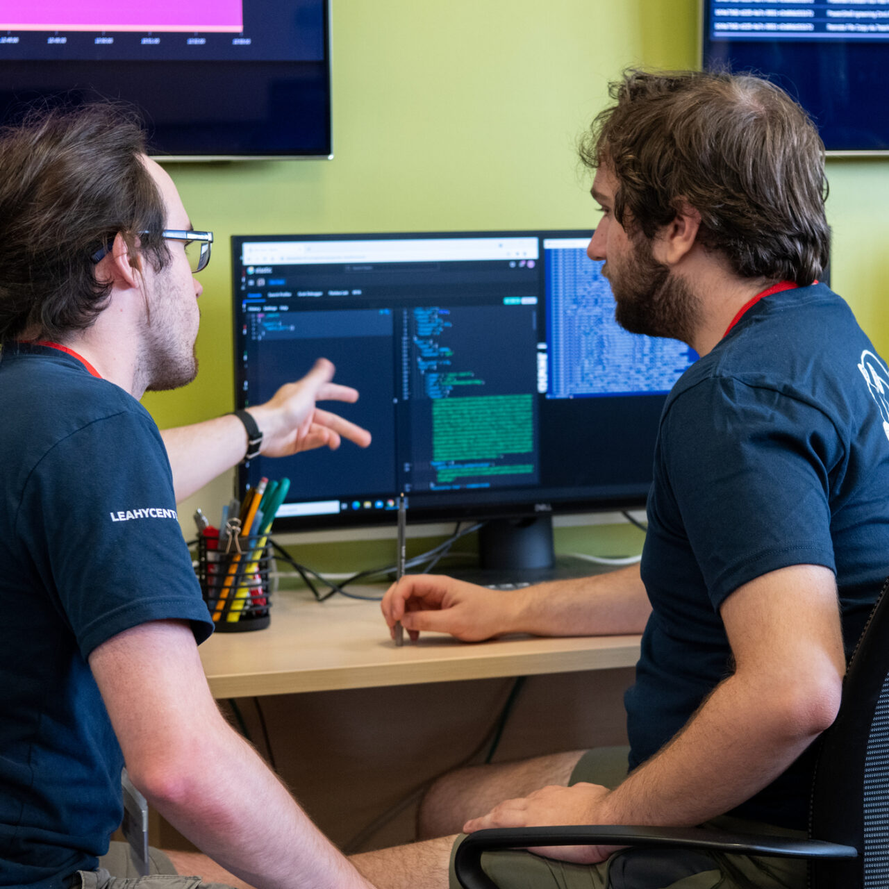 Two students looking at a computer screen and discussing programing